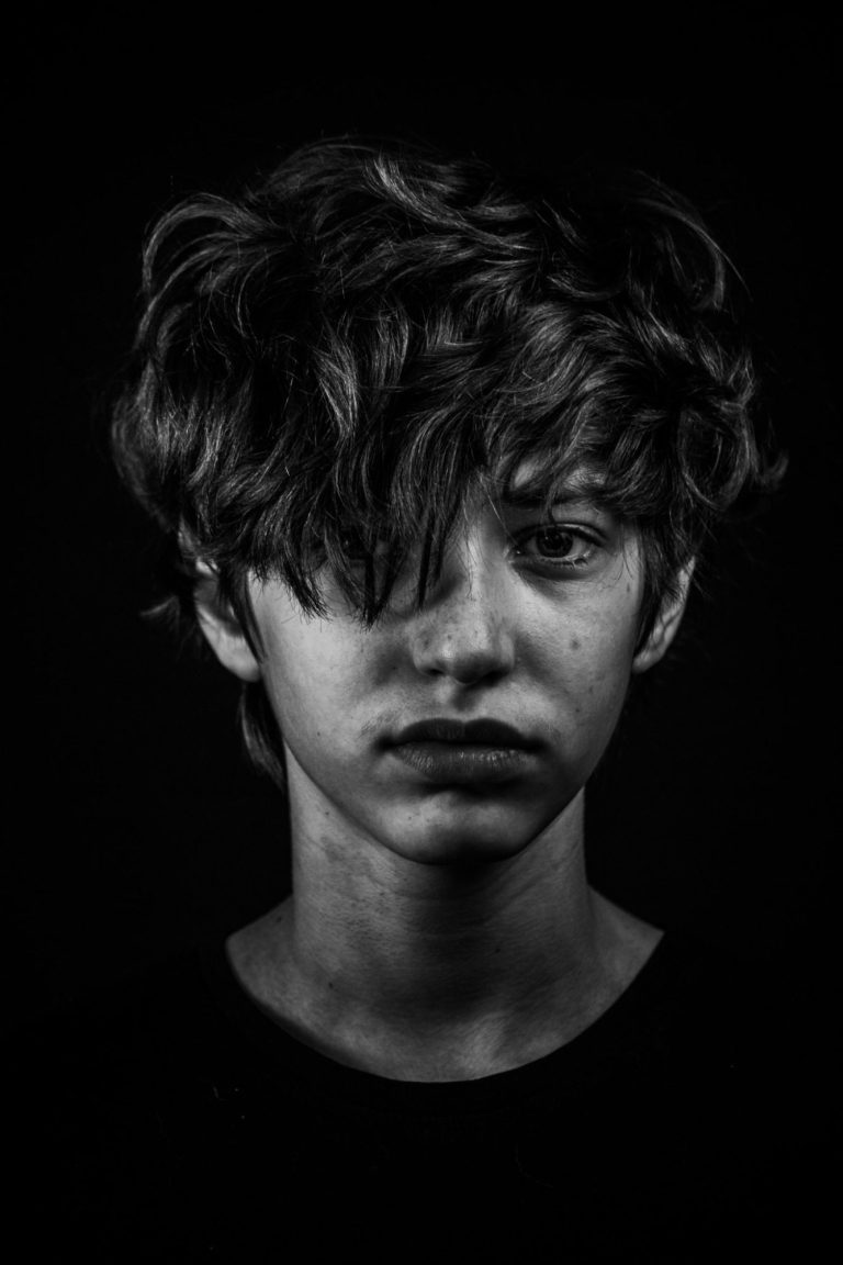 Portrait en noir et blanc d'un adolescent avec des cheveux en désordre, regard pensif.