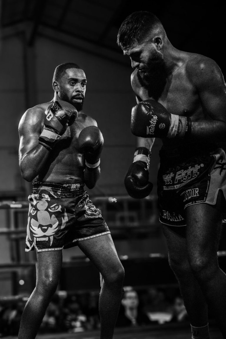 Deux boxeurs en action sur un ring, concentrés l'un sur l'autre.